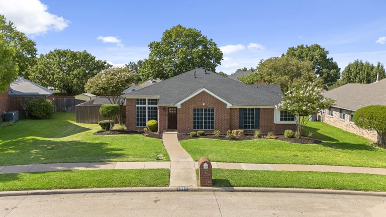 Aerial photograph of a home beside a tree-lined street