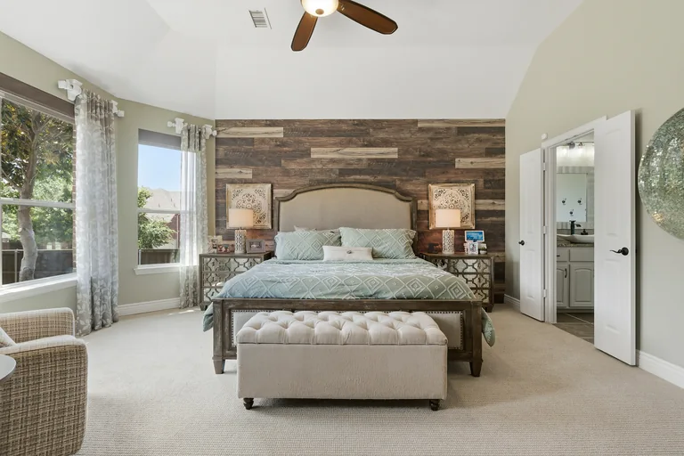 Bedroom with wood accent wall and backyard windows at 1000 Monticello Drive in Prosper