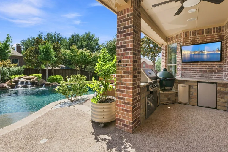 Covered patio and outdoor kitchen beside the pool at 1000 Monticello Drive in Prosper