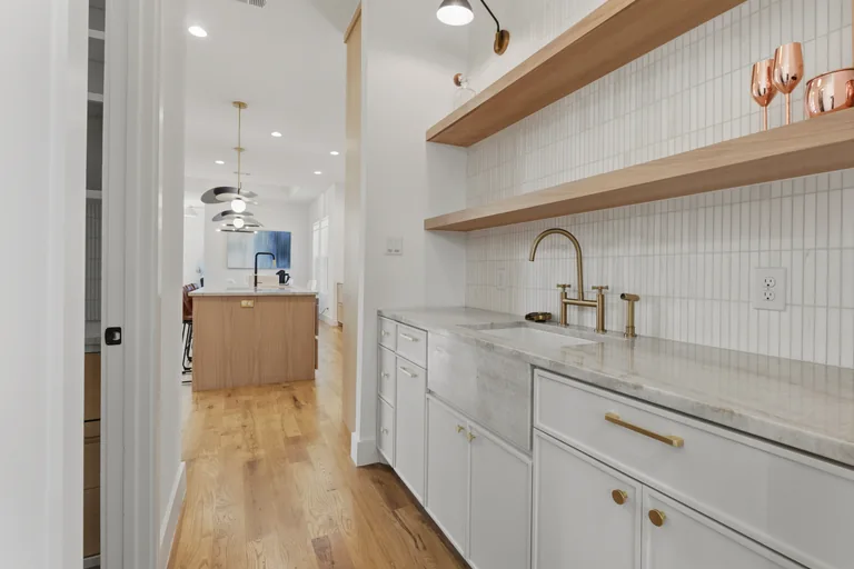 Butler's pantry with tile backsplash and open shelving at 3860 Walnut Hill Lane in Dallas