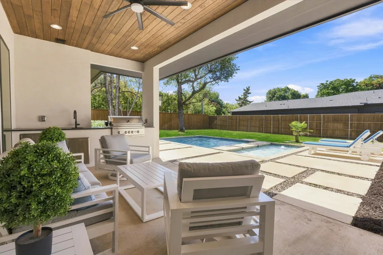 Covered patio lounge beside the pool at 3860 Walnut Hill Lane in Dallas