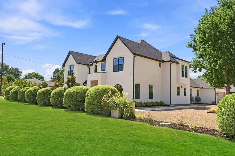 Street-level view of the front exterior and landscaping at 3860 Walnut Hill Lane in Dallas