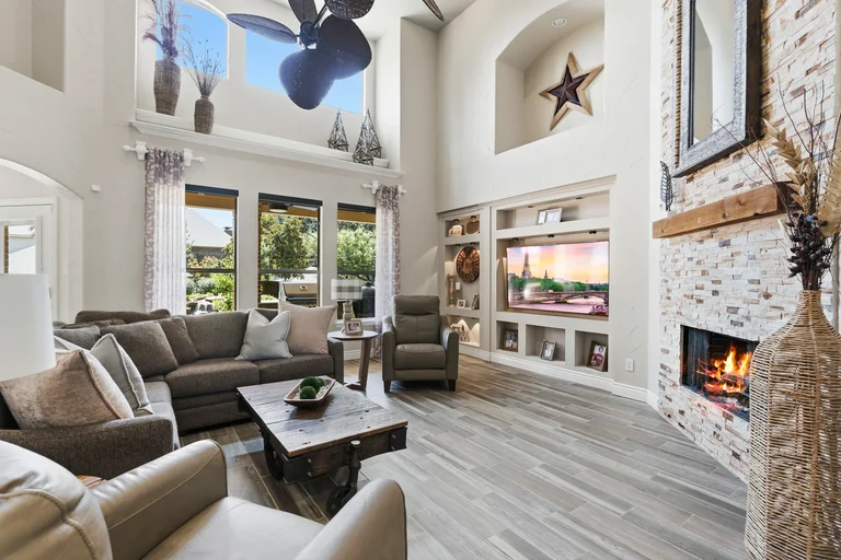 Living room with a stone fireplace, tall windows and a high ceiling at 1000 Monticello Drive in Prosper