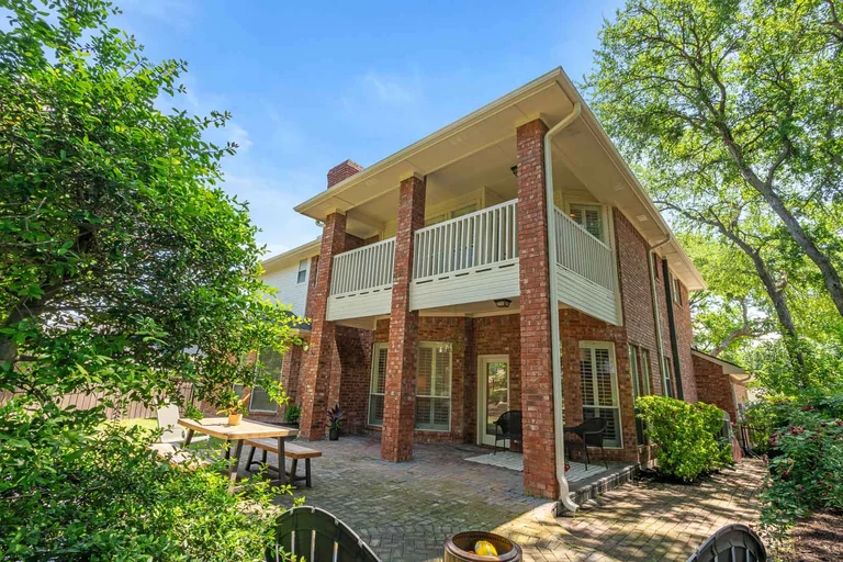 Rear exterior with brick columns, covered balconies and lawn — FLM media library example