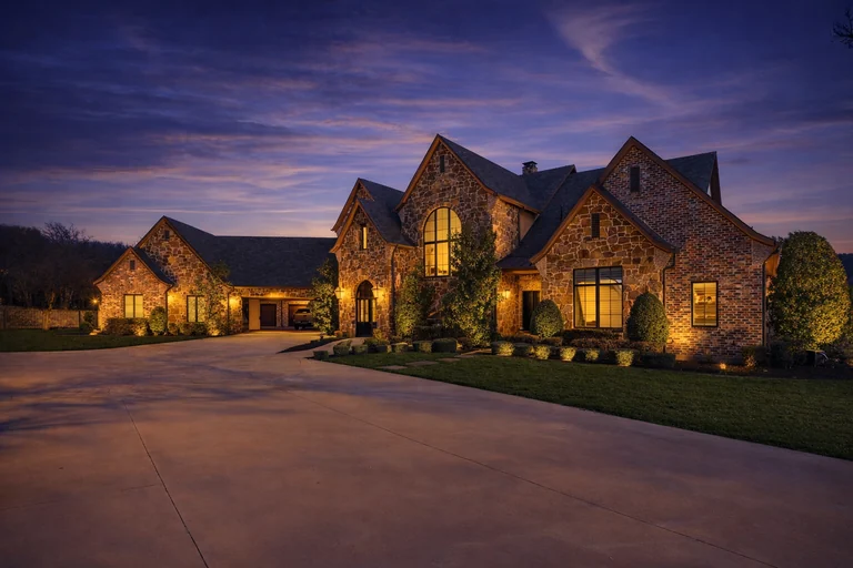 Evening exterior of a stone home with illuminated windows — FLM media library example