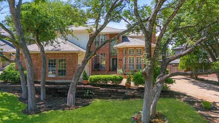 Front exterior and driveway seen through mature trees — FLM media library example