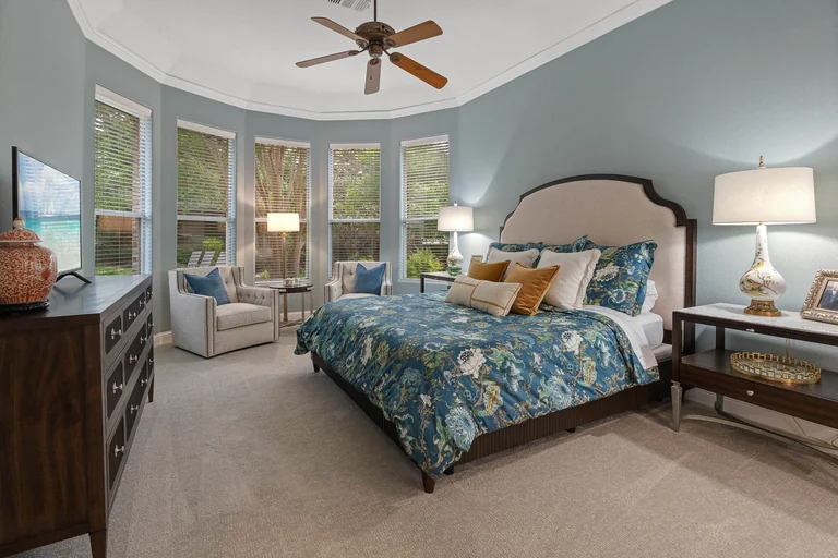 Bedroom with a wood accent wall, ceiling fan and backyard windows — FLM media library example
